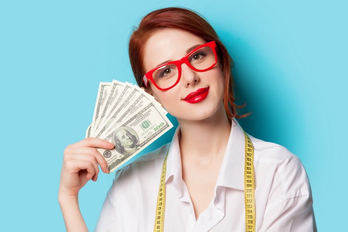 Redhead woman with glasses holding money