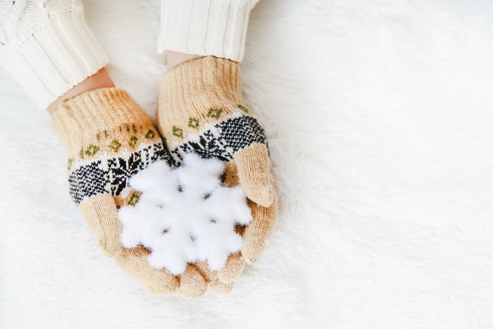Hands in Christmas gloves holding a snowflake
