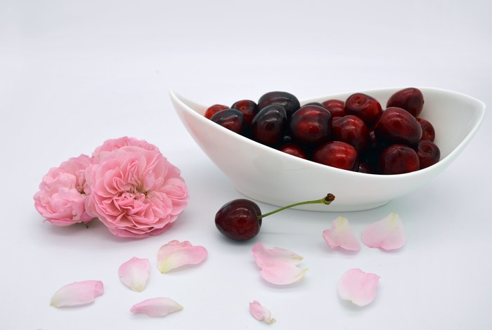 Cherries and pink roses on a white plate