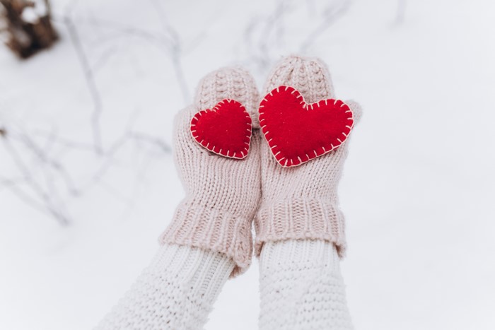 Two red hearts held by hands in mittens