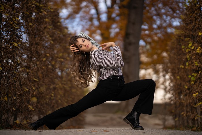 Woman in striped shirt and black trousers posing
