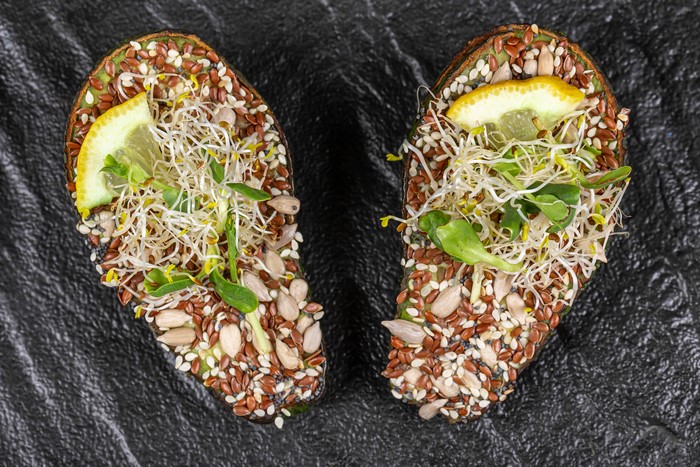 Avocado halves with sprouts and seeds