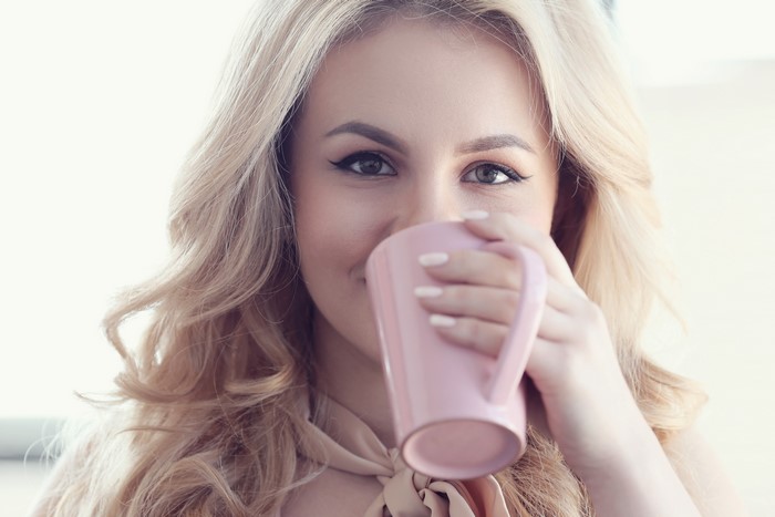 Blonde woman drinking from a pink mug