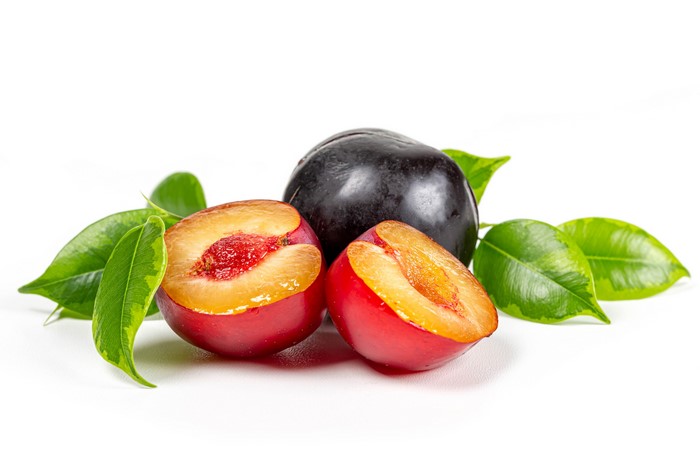 Plums with leaves on white background