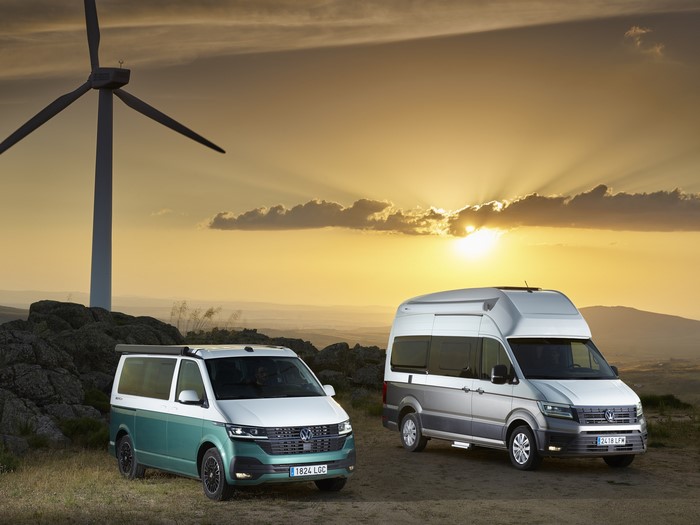 Two Volkswagen camper vans at sunset with wind turbine