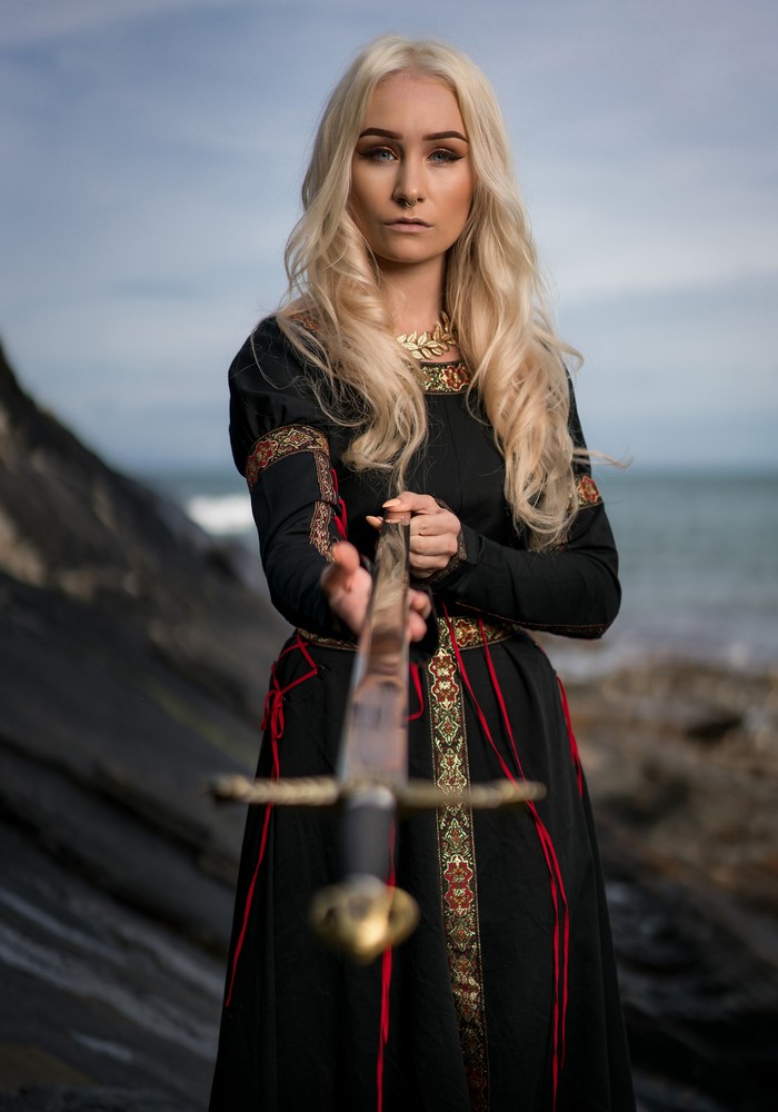 Blonde girl with sword on rocky shore