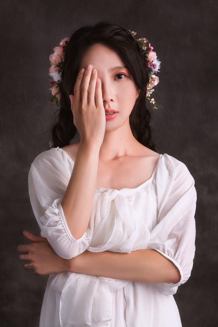 Asian woman with flower wreath covering eye