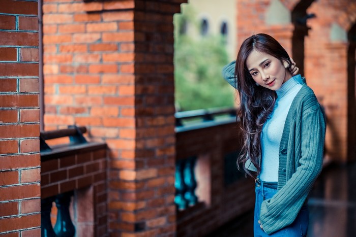 Asian woman posing near brick building