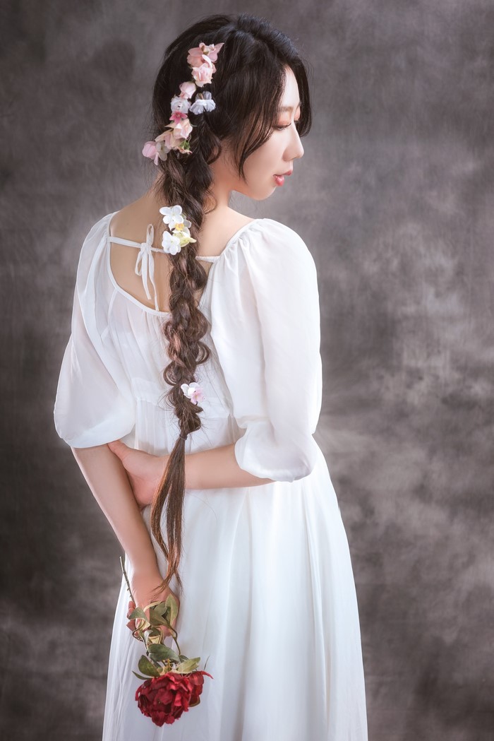 Asian woman with braid and flowers holding a rose