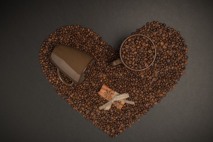 Coffee beans in a heart shape with mugs and cinnamon