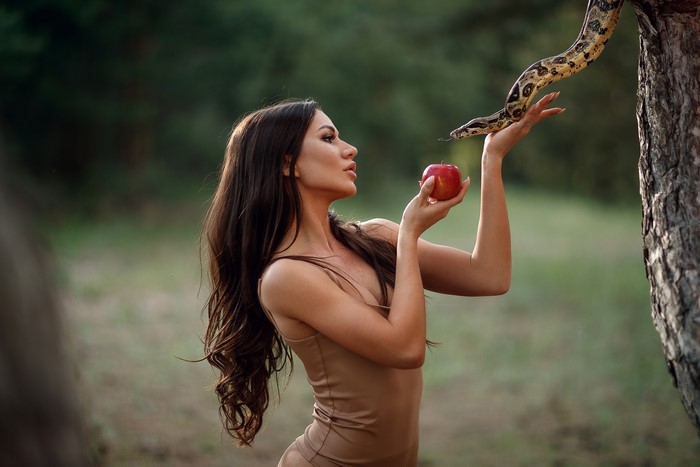 Woman with snake and apple in forest