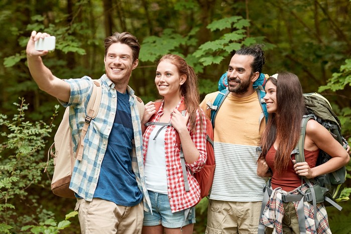 Four friends taking a selfie while hiking in a forest