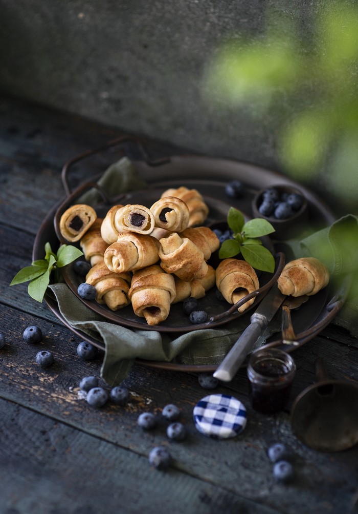 Mini croissants with blueberries on a dark wooden table