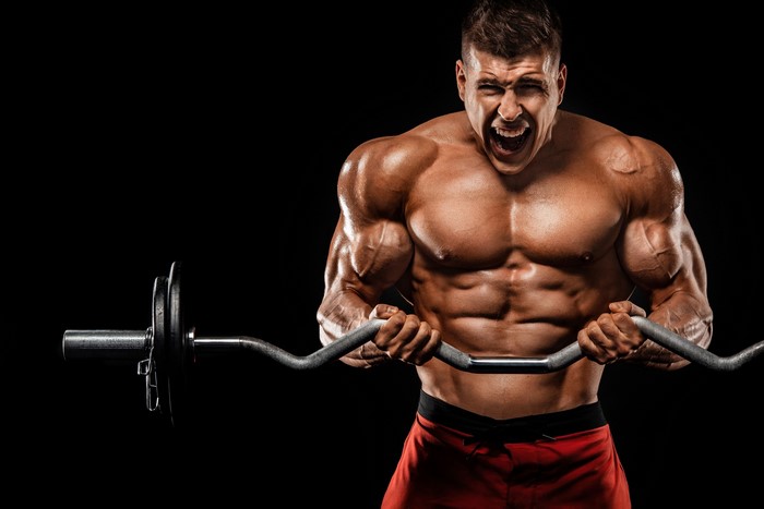 Bodybuilder performing barbell curls with intense expression
