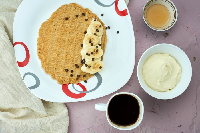 Pancake with bananas, chocolate chips, honey, sour cream, and coffee