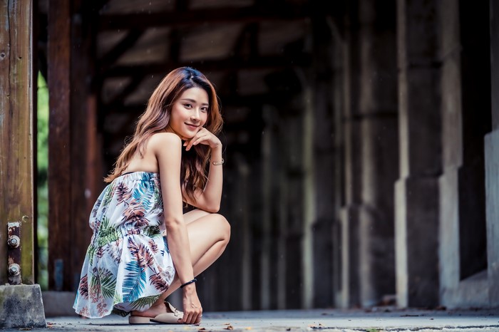 Asian woman in floral dress crouching