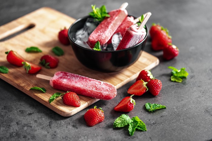 Strawberry popsicles in a bowl with ice and strawberries