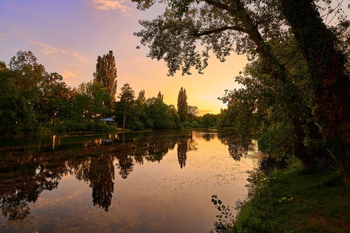 Sunset over a lake with trees and a gazebo
