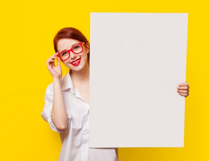 Redhead girl with glasses holding a blank sign
