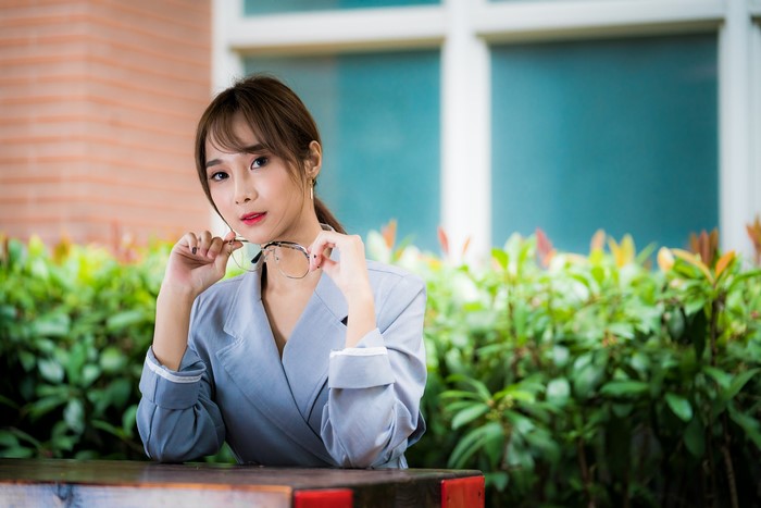 Asian woman with glasses sitting outdoors