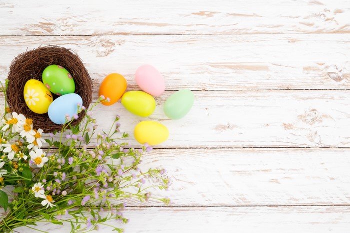 Easter eggs in a nest with flowers on wood planks