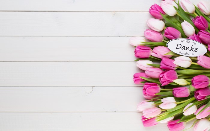 Pink and white tulips with 'Danke' card on wood planks