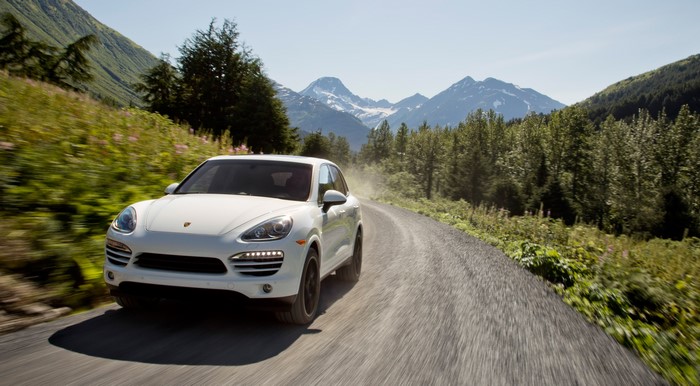 White Porsche Cayenne driving on a mountain road