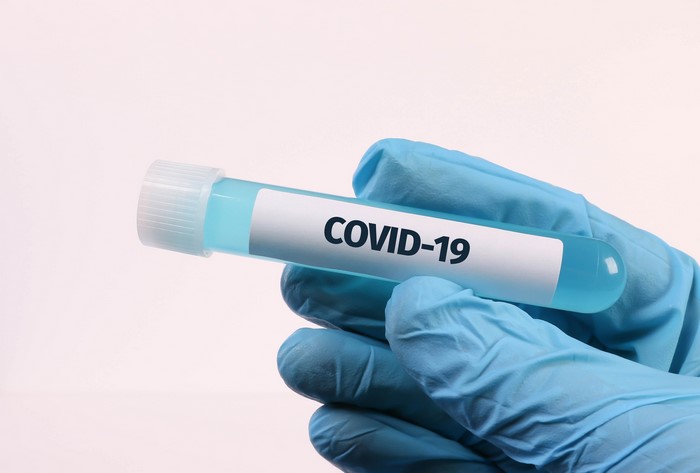 Hand in blue glove holding COVID-19 test tube
