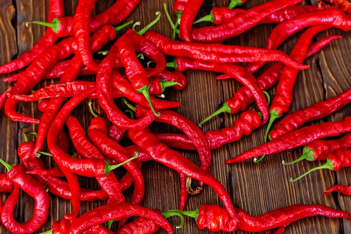 Pile of red chili peppers on a wooden surface