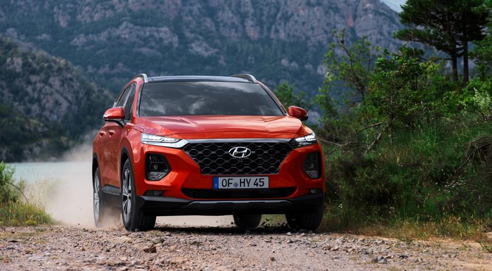 Red Hyundai Santa Fe driving on a dirt road