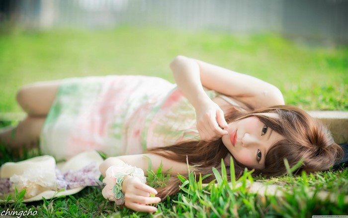 Asian woman with brown hair lying on grass