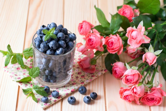 Blueberries in a glass with pink roses