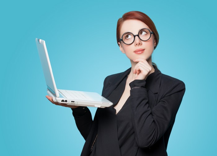 Redhead girl with glasses holding a laptop