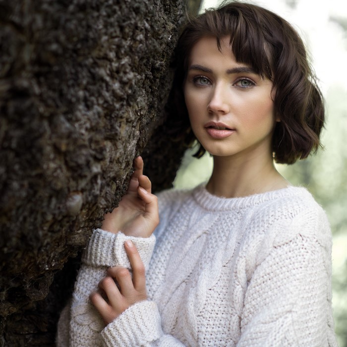 Brunette girl in a sweater by a tree