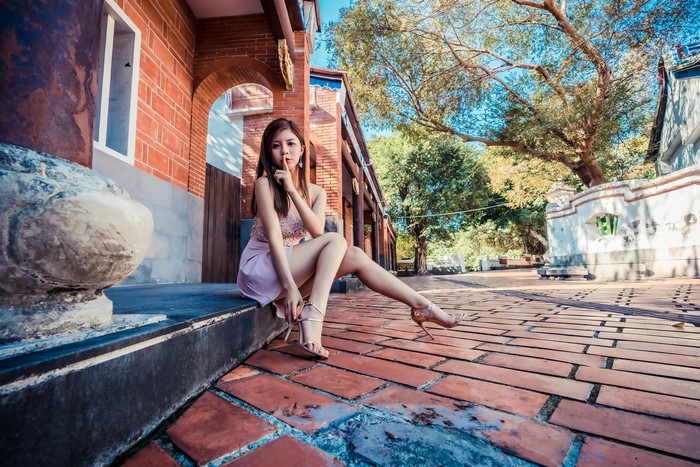 Asian woman sitting on steps, shushing gesture