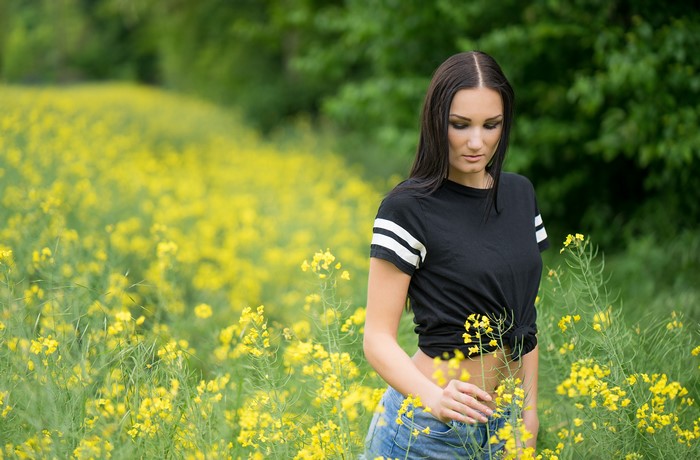 Brunette girl in t-shirt and shorts in rapeseed field