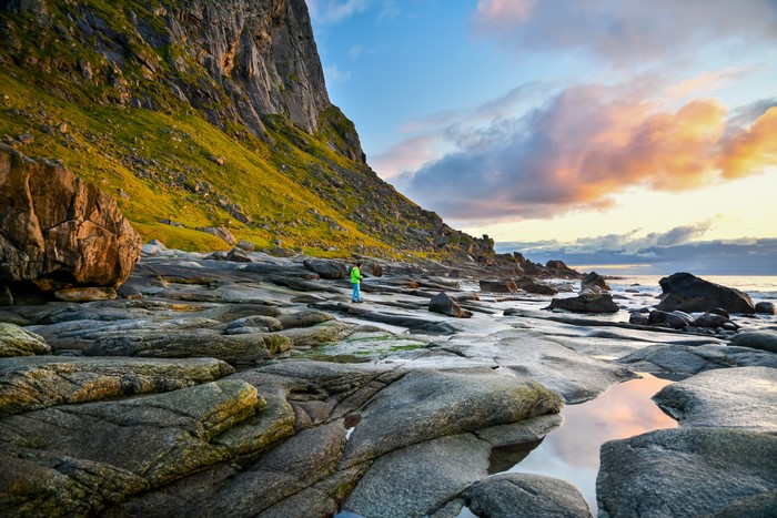 Person on rocky coast in Lofoten, Norway at sunset