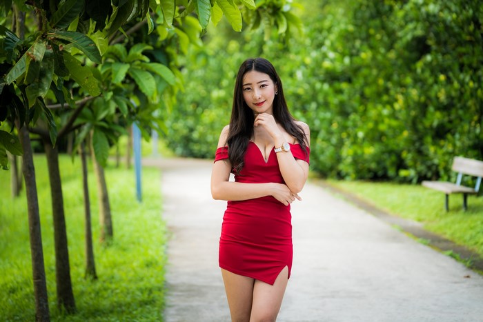 Asian woman in red dress posing in park