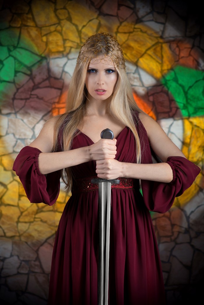 Blonde woman in a burgundy dress holding a sword