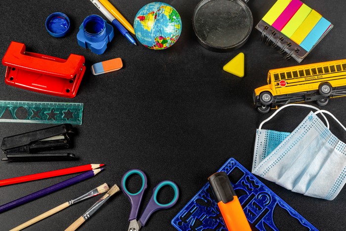 School supplies and a toy school bus on a black background