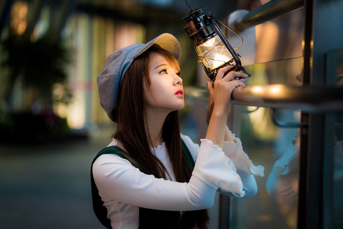 Asian girl with kerosene lamp wearing baseball cap