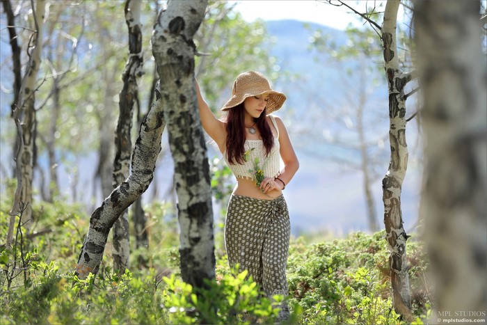 Elena Generi in a straw hat and skirt in a forest