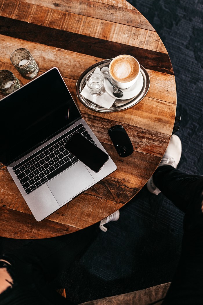 Laptop, Smartphone, Coffee, and Candles on a Wooden Table