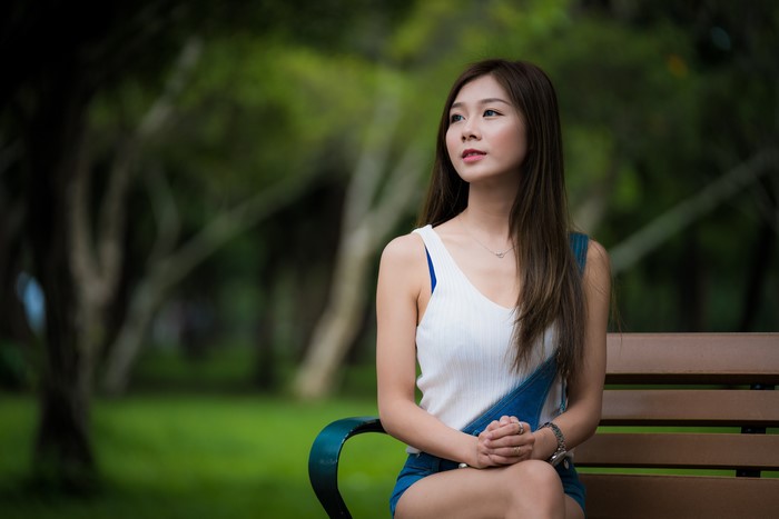 Asian woman with brown hair sitting on a bench