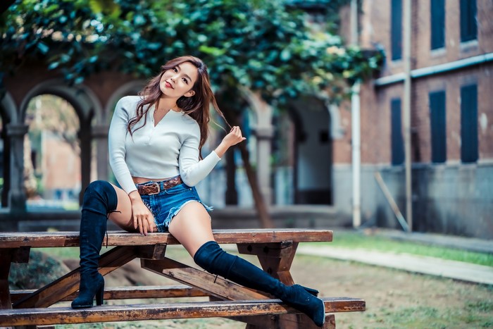 Asian woman sitting on a bench wearing shorts and boots