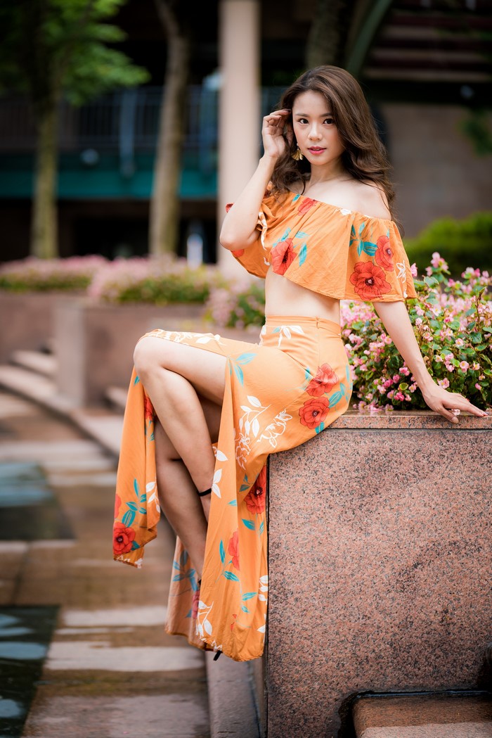 Asian woman in floral off-the-shoulder dress sitting outdoors