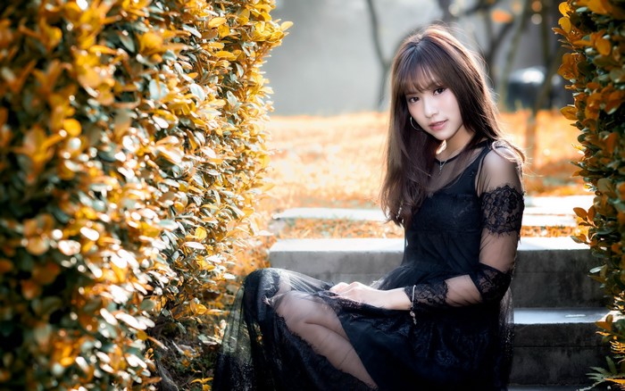 Asian Woman Sitting Among Golden Shrubs