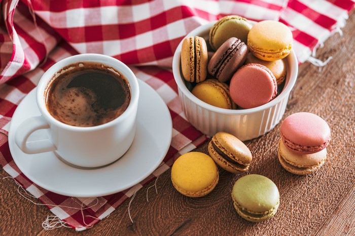 Coffee cup and macarons on a checkered cloth