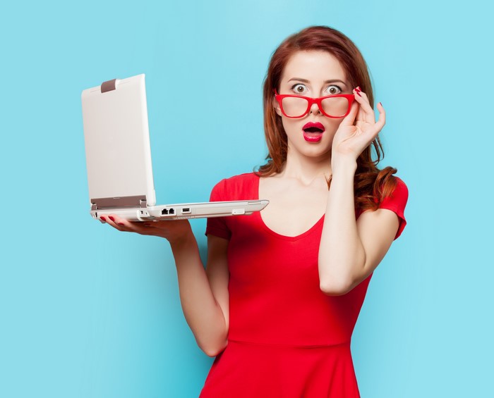 Redhead girl with glasses holding a laptop