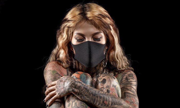 Tattooed woman wearing a black mask